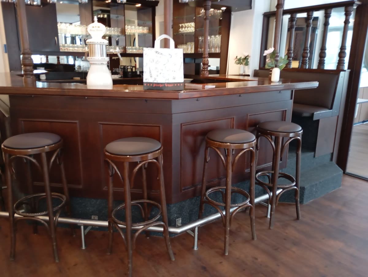 Vier neu bezogene Barhocker mit braunem Kunstleder an der Theke eines Restaurants