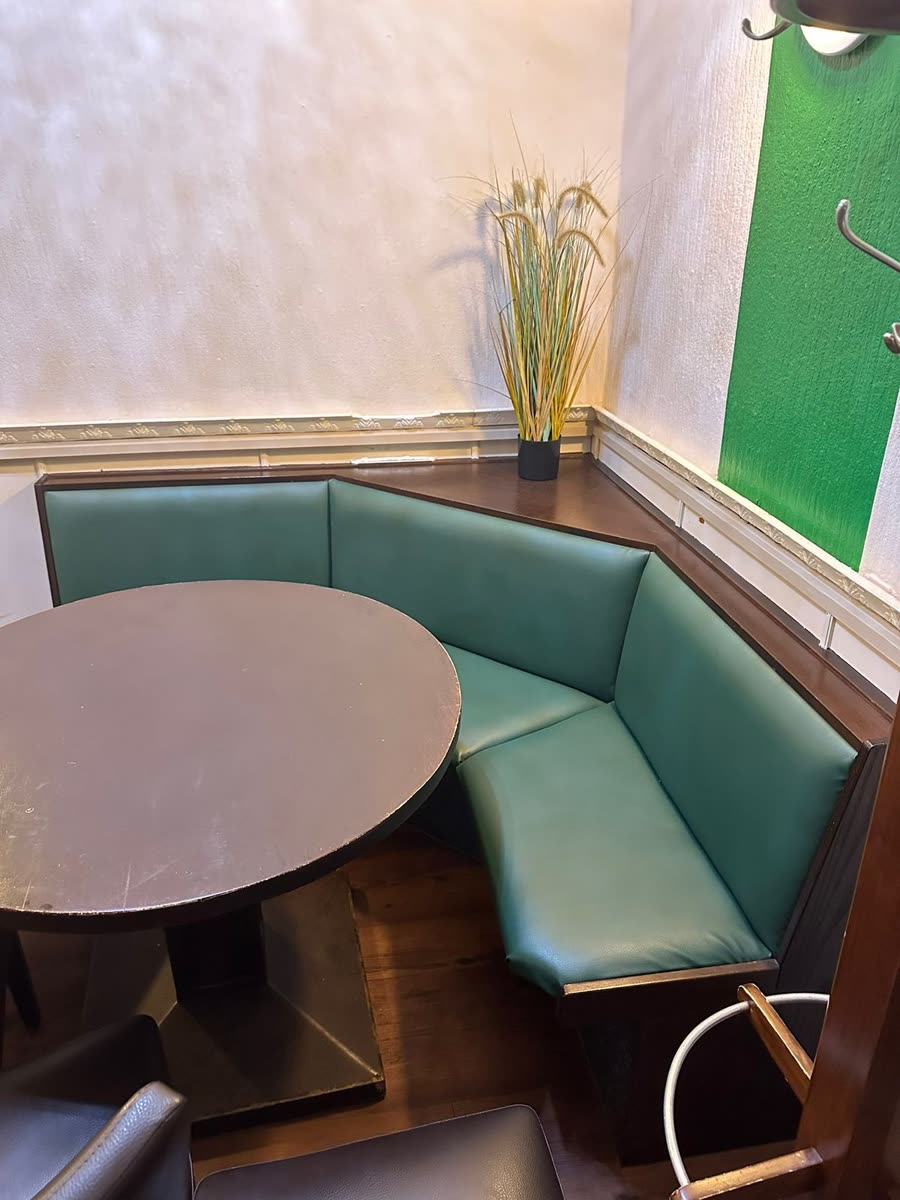 Eckbank in einem Restaurant mit altem grünem Kunstlederbezug vor der Neupolsterung