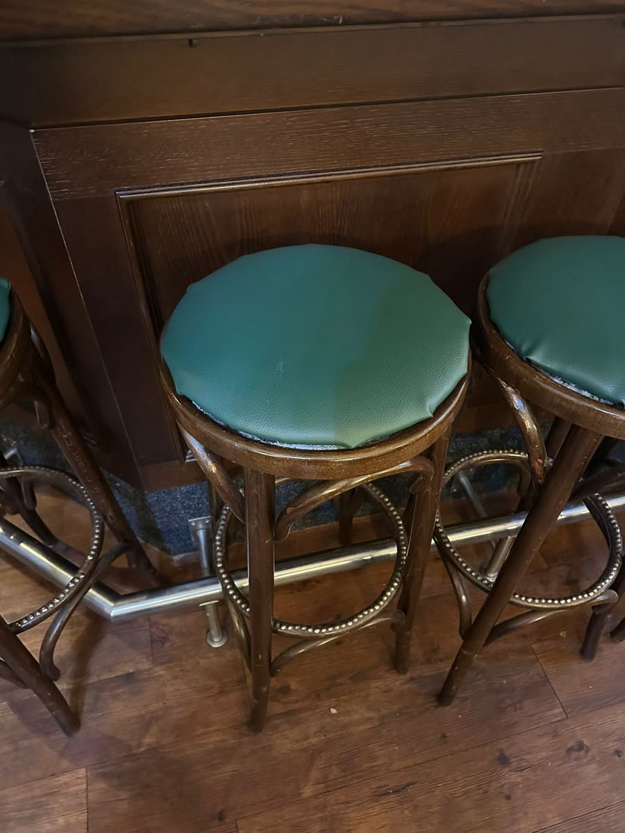 Barhocker in einem Restaurant mit abgenutzten grünen Kunstledersitzen vor der Neupolsterung